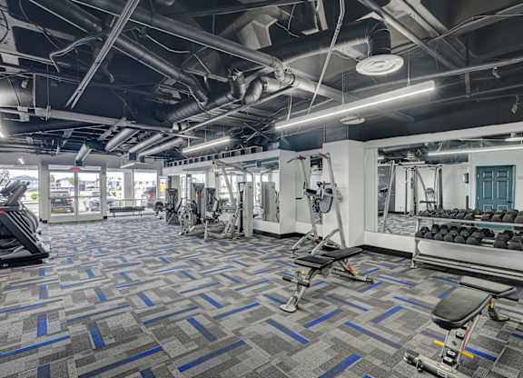 A gym with a variety of equipment including treadmills, weights, and exercise machines.