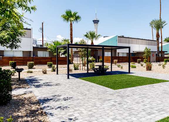 A building with a green roof and a white fence is surrounded by palm trees.