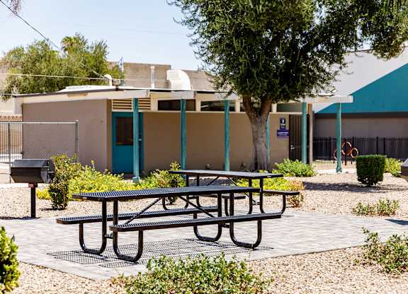 A picnic table is in front of a building with a blue door.