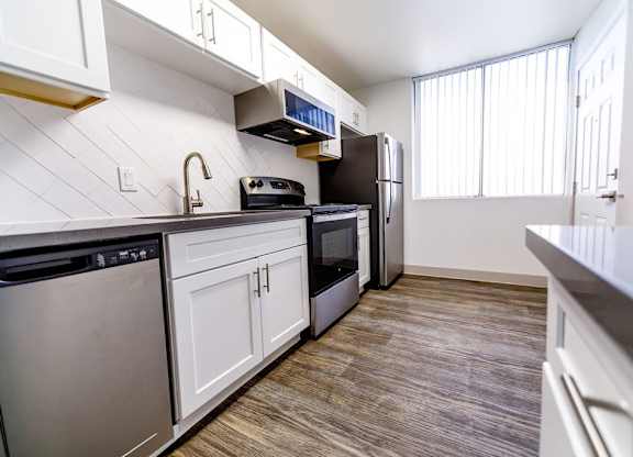A kitchen with white cabinets and a black fridge.