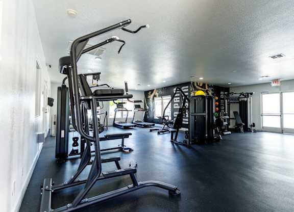 A gym with a variety of equipment including treadmills, weights, and exercise machines.