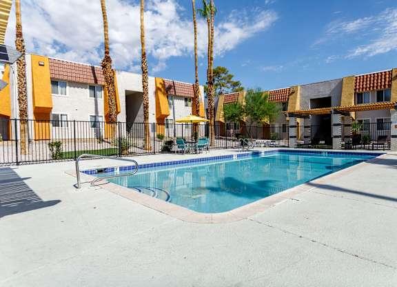 A swimming pool in front of a building with palm trees.