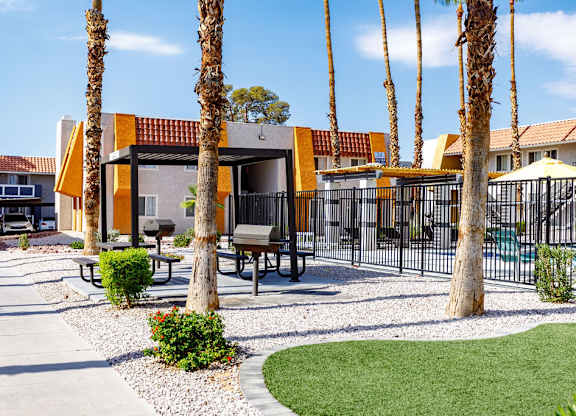 A yellow building with a red roof is surrounded by palm trees.