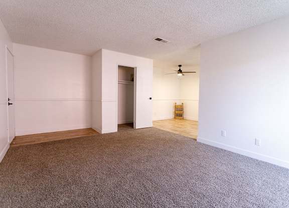A room with a carpeted floor and a ceiling fan.
