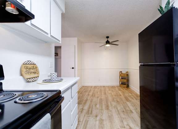 A kitchen with a black refrigerator and wooden floors.