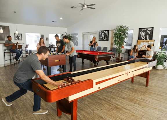A man is playing pool in a room with people sitting around.