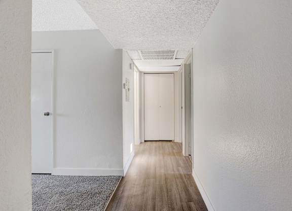 A long hallway with white walls and wood flooring.