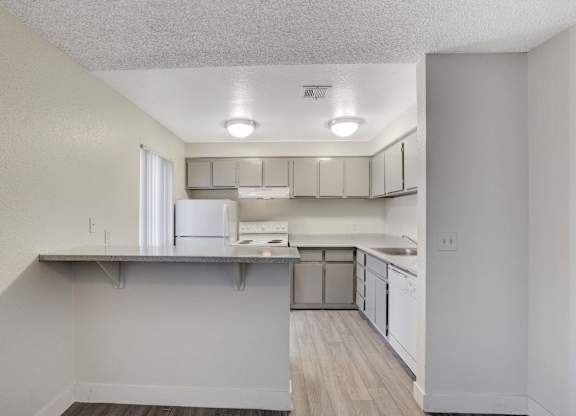 A kitchen with white cabinets and a refrigerator.