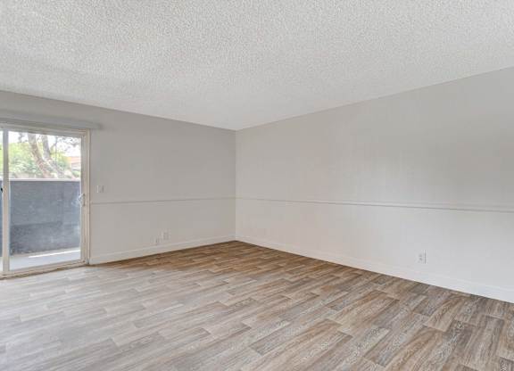 A room with wooden flooring and a sliding glass door.