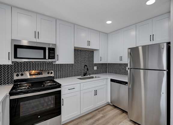 A modern kitchen with a stove, microwave, and refrigerator.
