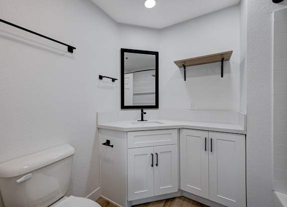 A white bathroom with a toilet, sink, and mirror.