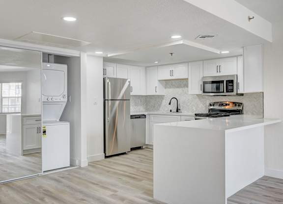 A modern kitchen with a white island and stainless steel appliances.