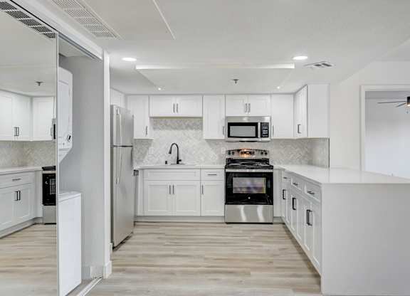 A modern kitchen with white cabinets and stainless steel appliances.