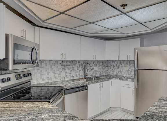 A kitchen with white cabinets and a granite counter top.