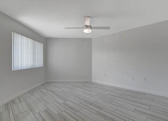 A room with a ceiling fan and a window with blinds.
