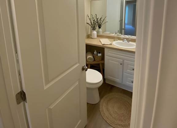 A white bathroom with a toilet, sink, and mirror.