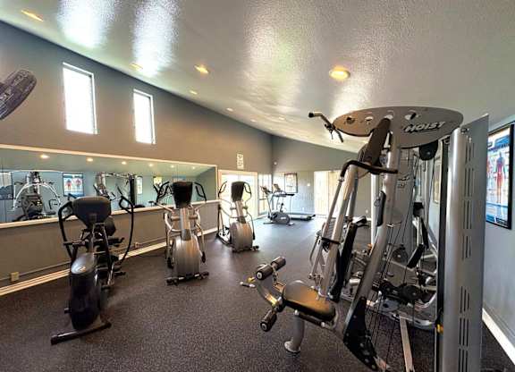 A gym with a variety of exercise equipment including treadmills, stationary bikes, and weight machines.