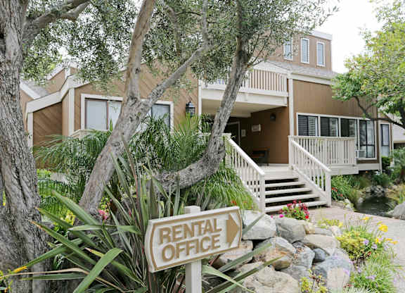 A rental office sign is in front of a two-story house.