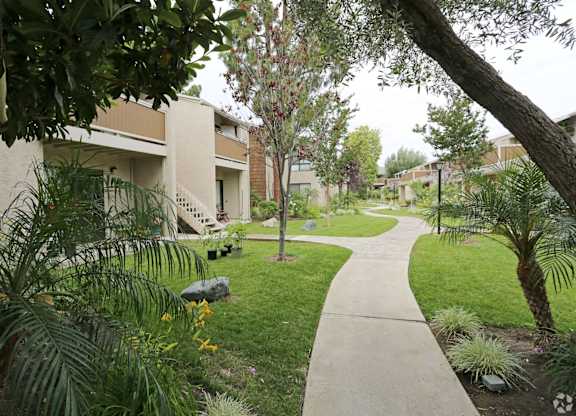 A pathway leads through a landscaped area with a building in the background.