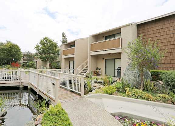 A bridge over a pond leads to a building.
