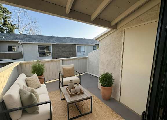 A patio with a couch, chair, and table.
