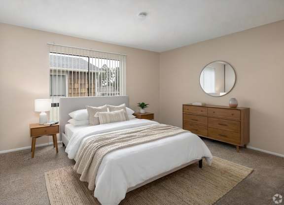 A bedroom with a large bed, a nightstand, and a window with blinds.