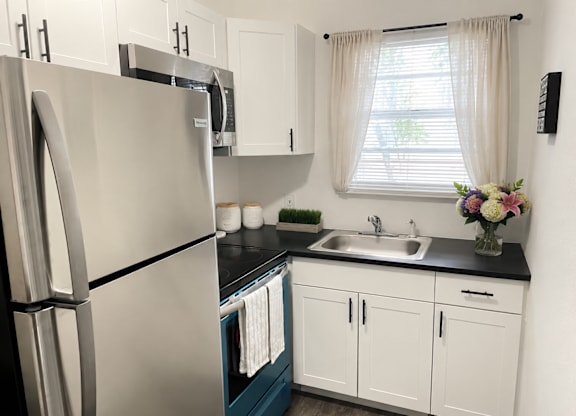 A kitchen with a stainless steel refrigerator and white cabinets.