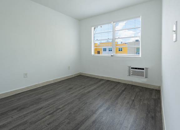 A room with a window and a vent on the wall.