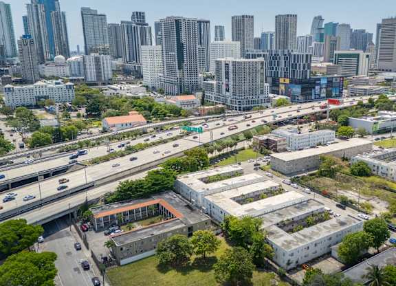A cityscape with a mix of modern and older buildings, a highway, and greenery.
