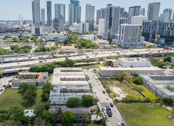 A cityscape with a mix of modern and older buildings, a highway, and green spaces.