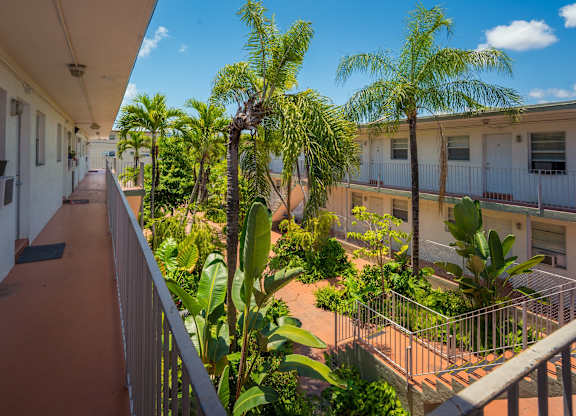 A balcony with a railing and a view of a building and trees.