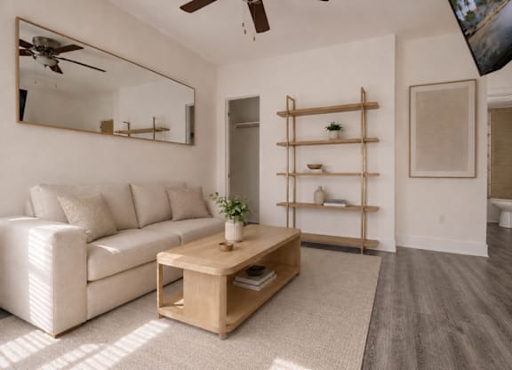 A living room with a white couch, a wooden coffee table, and a mirror on the wall.