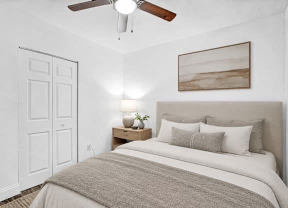 A bedroom with a bed, nightstand, and a ceiling fan.