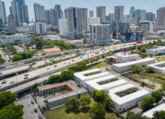 A cityscape with a mix of modern and older buildings, a highway, and greenery.