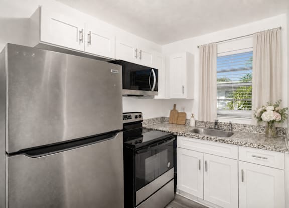 A modern kitchen with a stainless steel refrigerator and black oven.