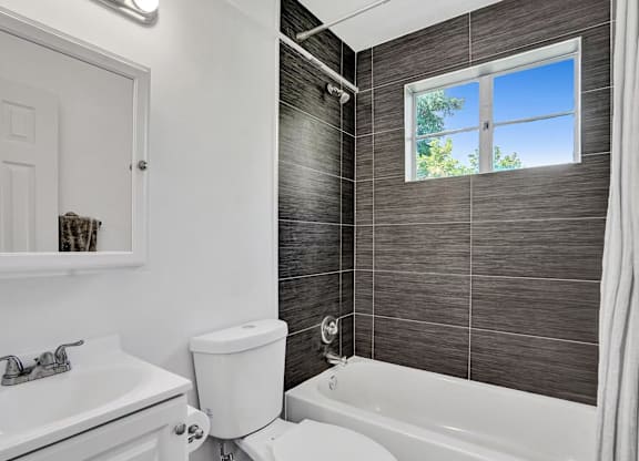 A bathroom with a white tub, toilet, and sink.