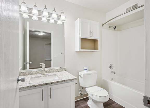 A white bathroom with a sink, toilet, and a mirror.