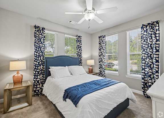 A bedroom with a large bed and a ceiling fan.