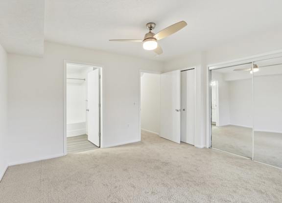 A room with a ceiling fan and carpeted floor.