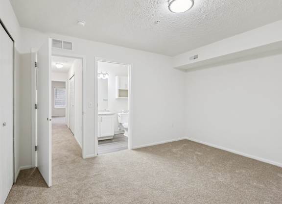 A white room with a carpeted floor and a doorway leading to another room.
