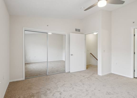 A spacious room with a carpeted floor and a ceiling fan.