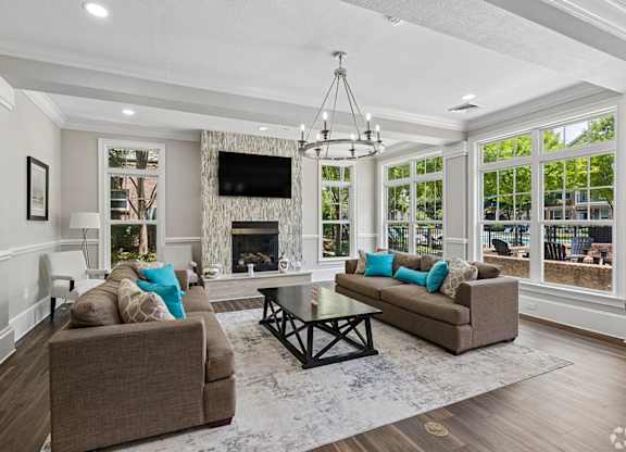 A living room with a brown couch, a fireplace, and a chandelier.