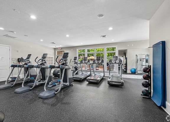 A gym with treadmills, elliptical machines, and weights.