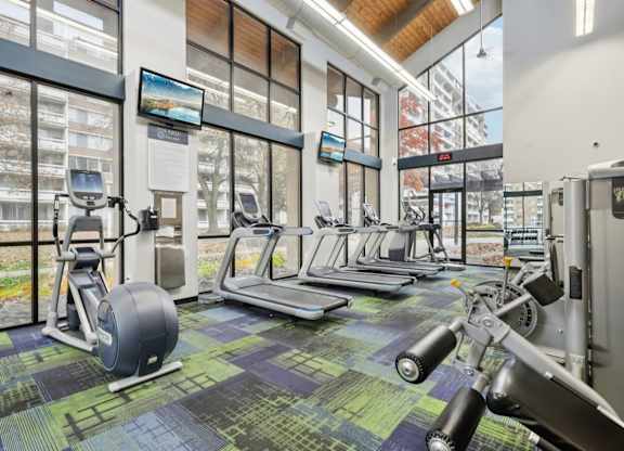 A gym with a variety of equipment including treadmills, stationary bikes, and weight machines.