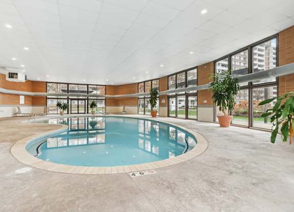 A large indoor swimming pool with a white ceiling and brick walls.