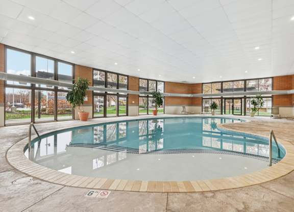 A round indoor swimming pool with a glass barrier.