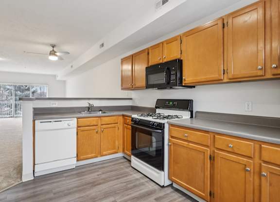 A kitchen with wooden cabinets and a black microwave above the stove.