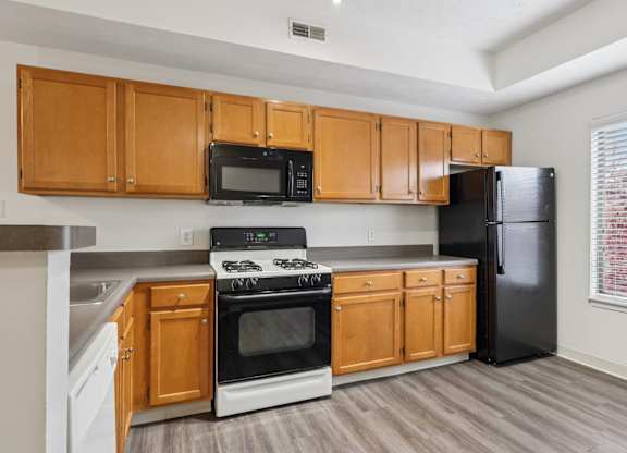 A kitchen with wooden cabinets and a black refrigerator.