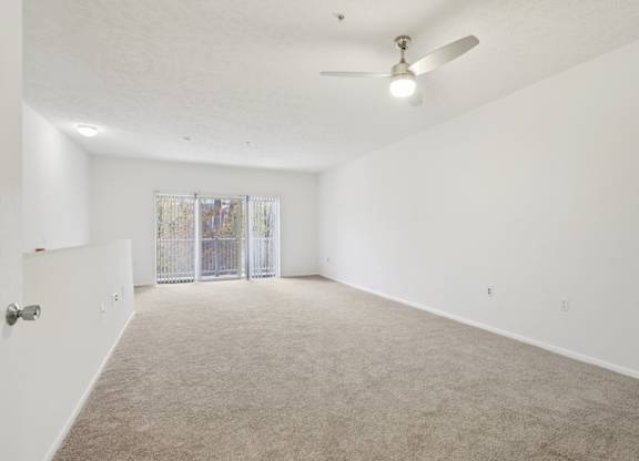 A spacious room with a ceiling fan and carpeted floor.