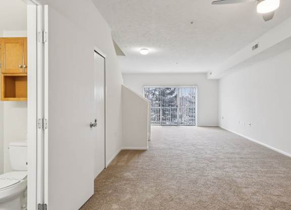 A spacious, empty room with a carpeted floor and white walls.